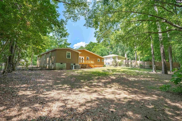 view of yard with fence, a wooden deck, and central AC unit