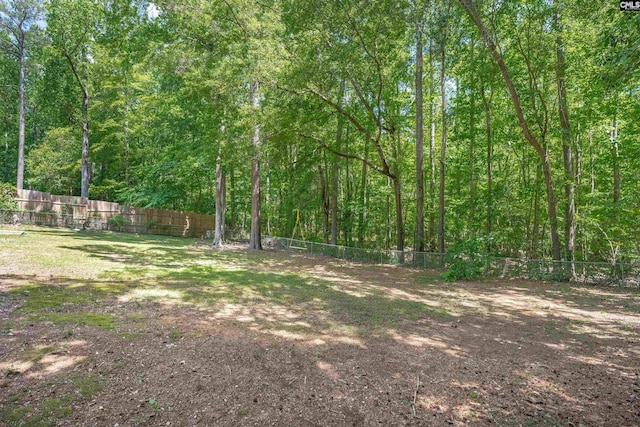 fenced backyard with a forest view