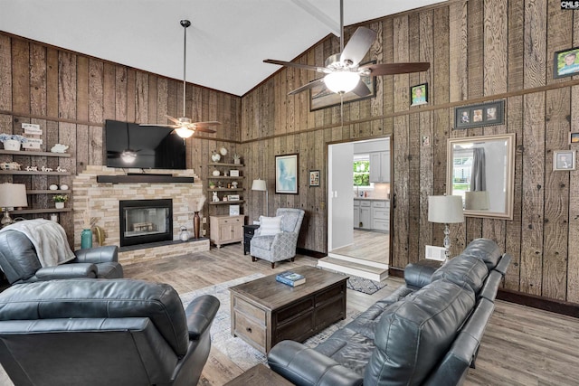 living area featuring high vaulted ceiling, wood finished floors, a ceiling fan, beam ceiling, and wooden walls