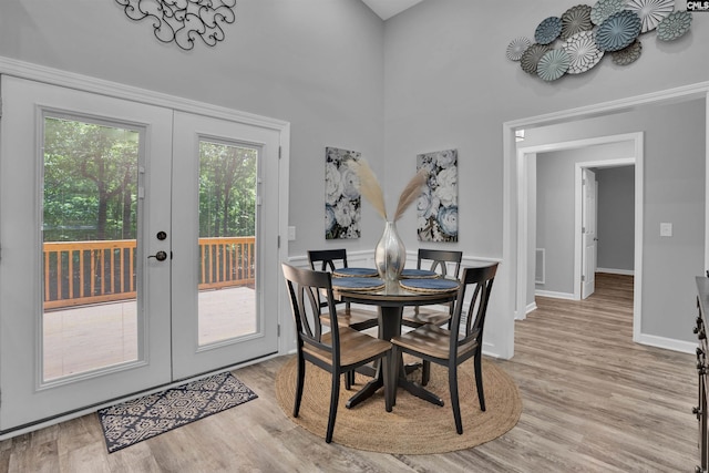 dining room featuring french doors, light wood-type flooring, and baseboards