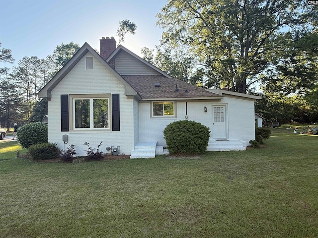 1006 W Main, Ridge Spring, SC 29129 - view of home's exterior with brick siding, a chimney, a yard, and roof with shingles