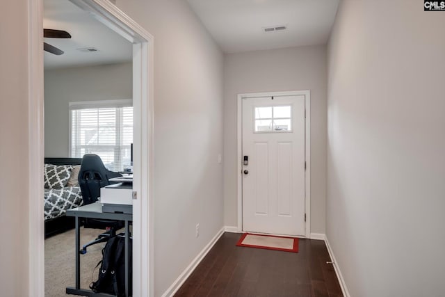 doorway with dark wood finished floors, a desk, baseboards, and ceiling fan