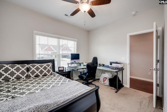 bedroom with light colored carpet, a desk, baseboards, and a ceiling fan