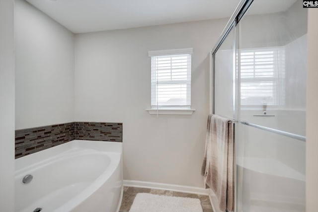 full bathroom with a garden tub, a stall shower, baseboards, and tile patterned floors