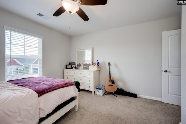 bedroom featuring multiple windows, light colored carpet, a ceiling fan, and baseboards