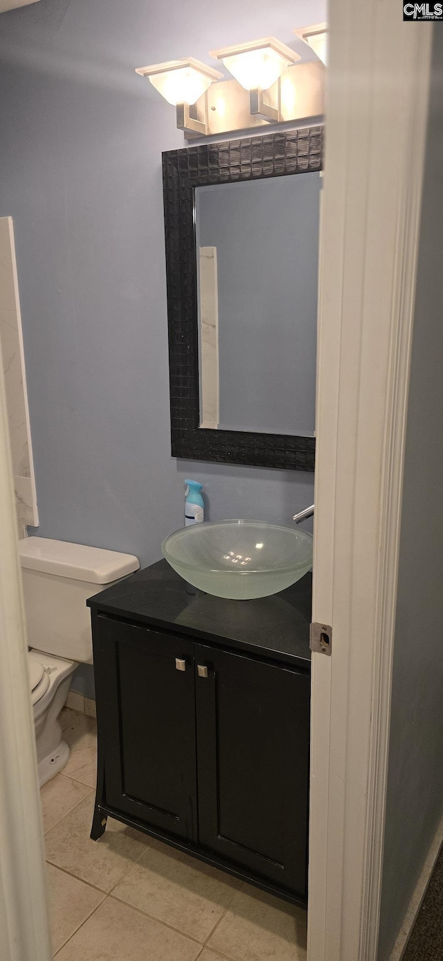 half bath featuring vanity, tile patterned floors, and toilet