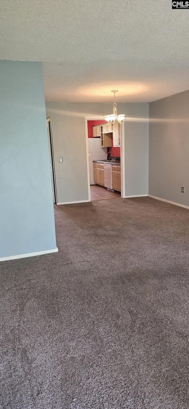 unfurnished living room with light carpet, a textured ceiling, baseboards, and a chandelier