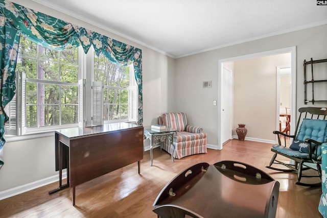 living area with ornamental molding, wood finished floors, and baseboards