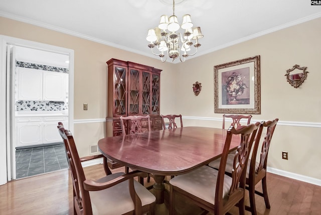 dining space with wood finished floors, a chandelier, ornamental molding, and baseboards