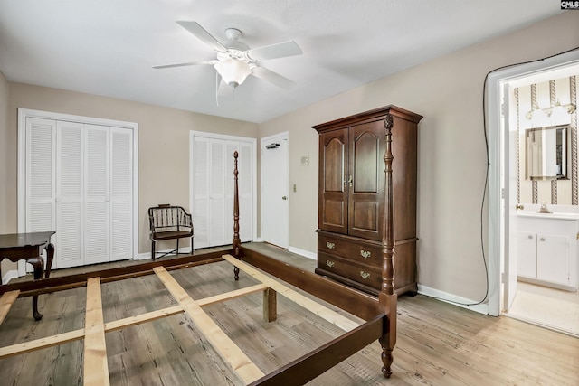 bedroom featuring multiple closets, light wood-style flooring, baseboards, connected bathroom, and a sink