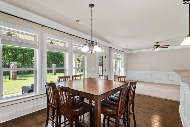 dining area with a chandelier, dark wood-style flooring, a wainscoted wall, a ceiling fan, and a decorative wall