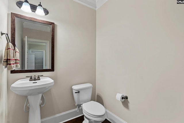 bathroom with crown molding, baseboards, toilet, and wood finished floors