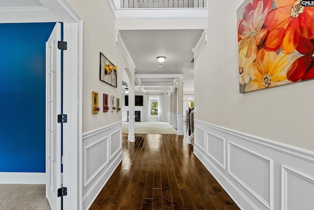 corridor with crown molding, a decorative wall, a wainscoted wall, and hardwood / wood-style floors