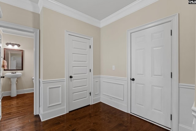 hall featuring a wainscoted wall, ornamental molding, and dark wood-style flooring
