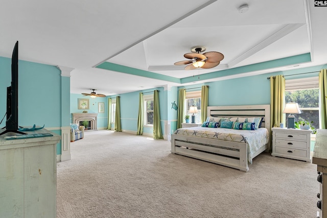 bedroom featuring a fireplace, carpet floors, multiple windows, and a tray ceiling