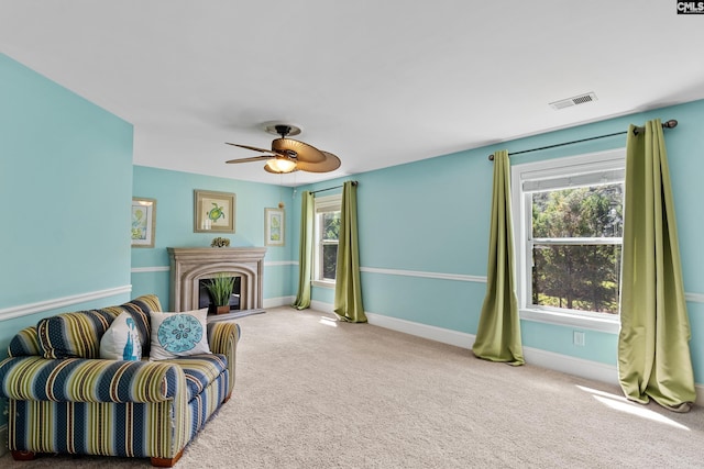 carpeted living area with healthy amount of natural light, a ceiling fan, and baseboards
