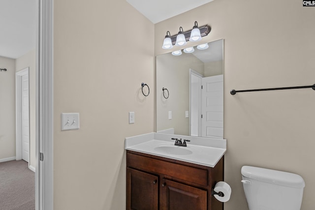 bathroom featuring toilet, vanity, and baseboards