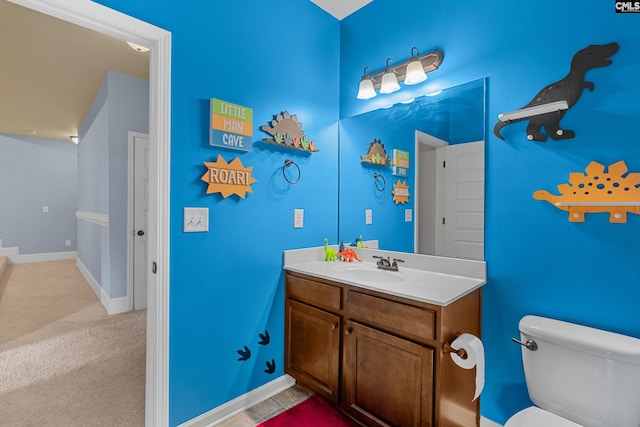half bath featuring toilet, vanity, and baseboards