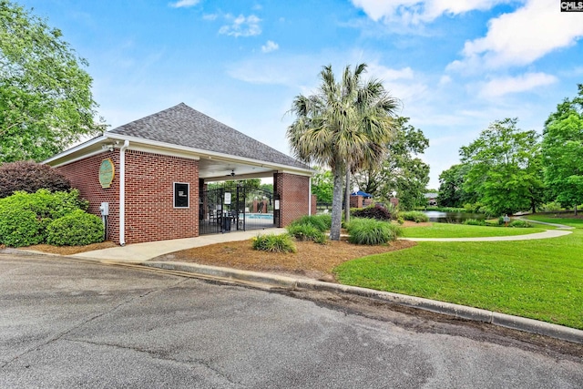 view of side of home with brick siding, a lawn, concrete driveway, a carport, and roof with shingles