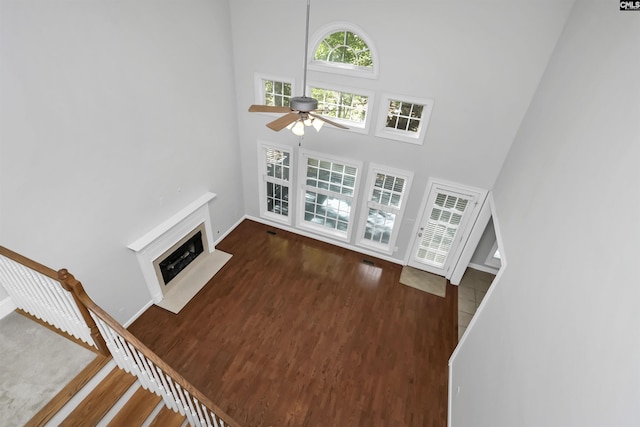 5 Stonewall Ct, Irmo, SC 29063 - unfurnished living room featuring wood finished floors, a ceiling fan, a towering ceiling, a fireplace with flush hearth, and baseboards