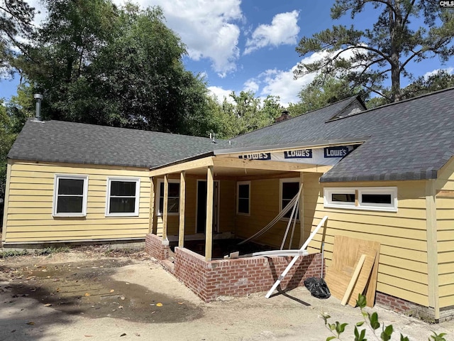 rear view of property with roof with shingles
