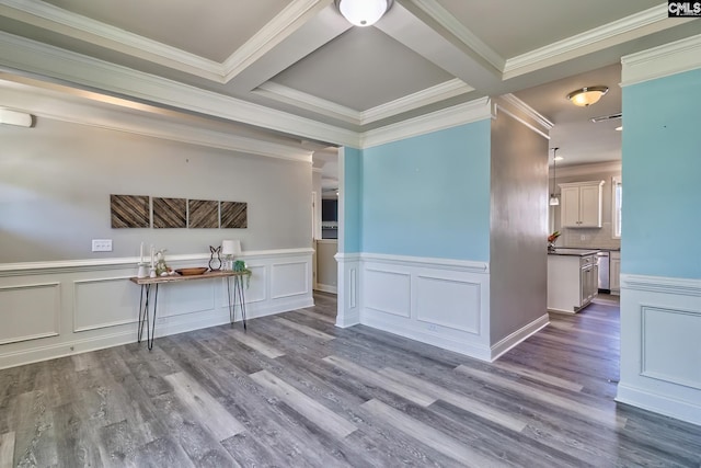 spare room featuring wood finished floors, crown molding, a wainscoted wall, beam ceiling, and coffered ceiling