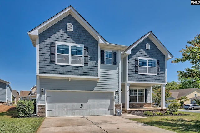 view of front of house featuring a garage, stone siding, driveway, and a porch