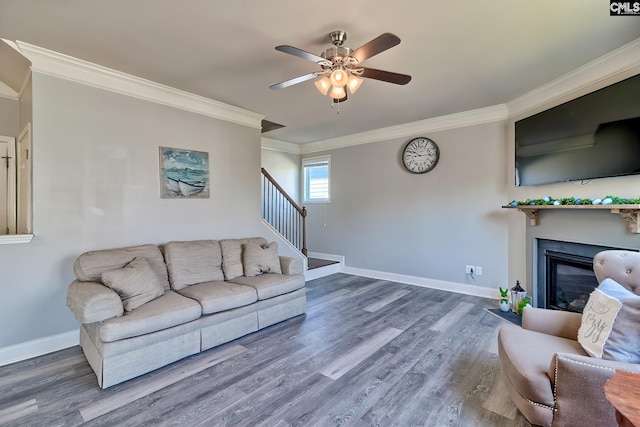 living room with ornamental molding, stairway, baseboards, ceiling fan, and wood finished floors