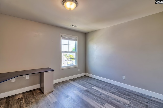 spare room featuring dark wood finished floors and baseboards