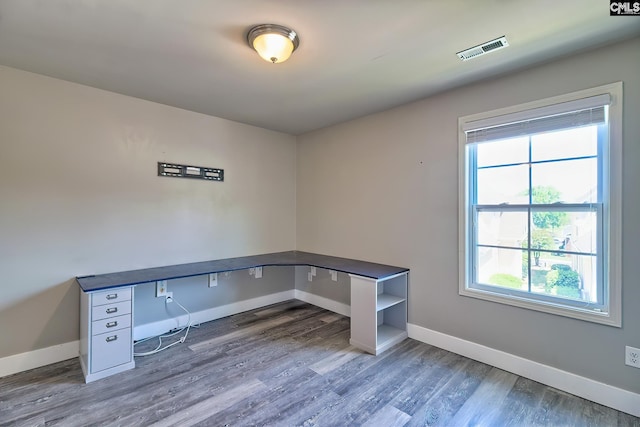 unfurnished office featuring plenty of natural light, baseboards, and wood finished floors