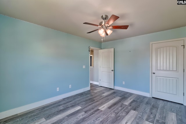 unfurnished bedroom with wood finished floors, baseboards, and a ceiling fan