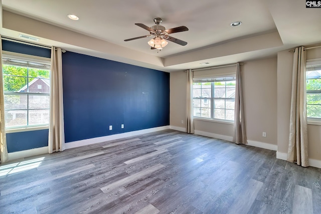 unfurnished room featuring ceiling fan, a raised ceiling, baseboards, wood finished floors, and recessed lighting