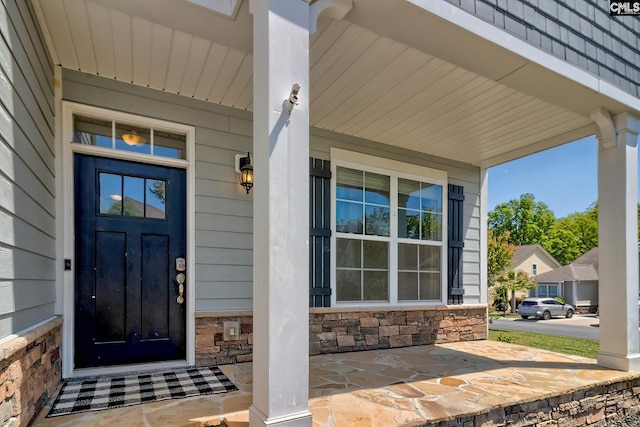 view of exterior entry featuring covered porch and stone siding