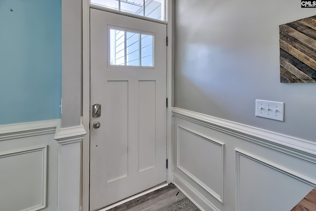 entryway featuring wainscoting, a decorative wall, and wood finished floors
