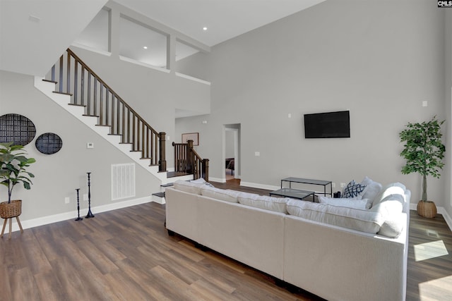 living area with stairway, dark wood-type flooring, a high ceiling, and baseboards