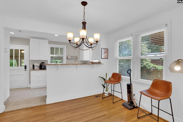 3803 Yale Ave, Columbia, SC 29205 - kitchen featuring a kitchen breakfast bar, white cabinets, plenty of natural light, a chandelier, and recessed lighting