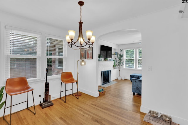 3803 Yale Ave, Columbia, SC 29205 - dining room featuring light wood-style flooring, arched walkways, a brick fireplace, a chandelier, and baseboards