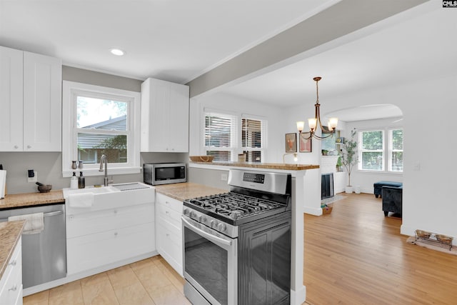 3803 Yale Ave, Columbia, SC 29205 - kitchen featuring stainless steel appliances, a sink, a peninsula, white cabinets, and a chandelier