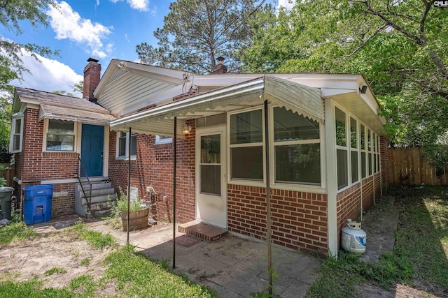 3803 Yale Ave, Columbia, SC 29205 - rear view of house featuring entry steps, brick siding, a chimney, fence, and a patio