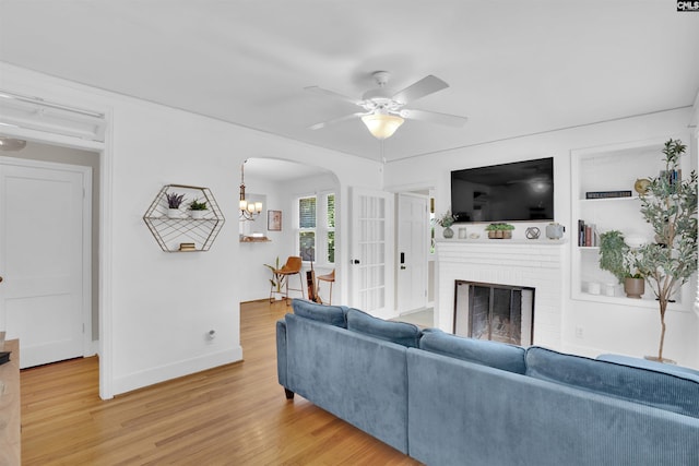 3803 Yale Ave, Columbia, SC 29205 - living area featuring arched walkways, light wood finished floors, ceiling fan, a brick fireplace, and baseboards