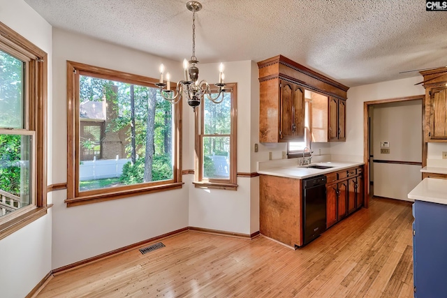 kitchen with black dishwasher, a chandelier, light countertops, light wood finished floors, and a textured ceiling