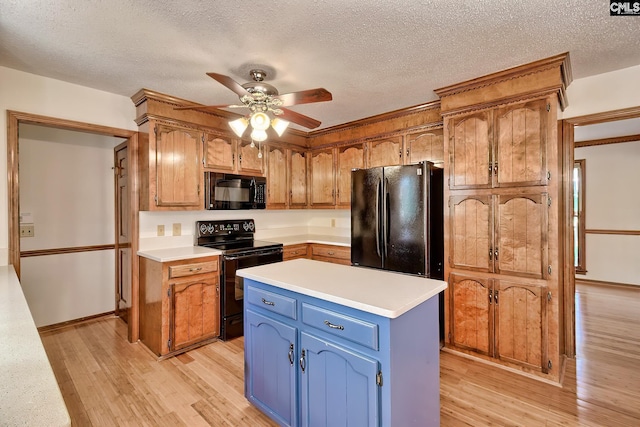 kitchen featuring black appliances, light wood-type flooring, light countertops, blue cabinetry, and a ceiling fan