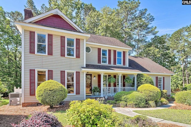 view of front of home featuring covered porch, a chimney, central AC, and roof with shingles