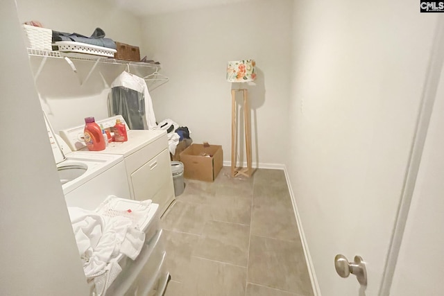clothes washing area featuring washer and clothes dryer, baseboards, and light tile patterned floors