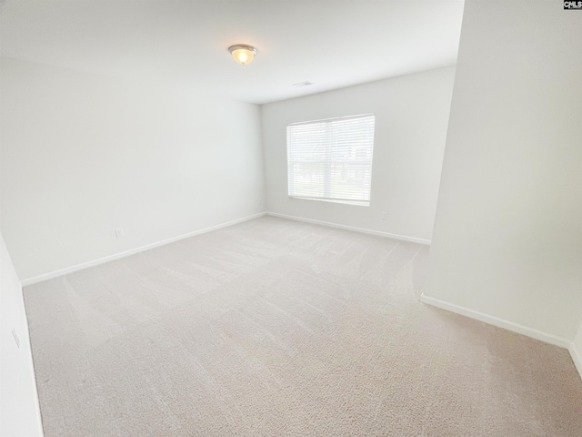 unfurnished room featuring light carpet and baseboards