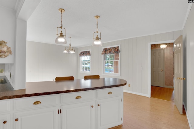 604 Shady Ln, Cayce, SC 29033 - kitchen featuring dark countertops, light wood-style floors, a peninsula, ornamental molding, and white cabinets