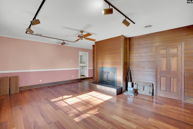604 Shady Ln, Cayce, SC 29033 - unfurnished living room with track lighting, a tiled fireplace, wood finished floors, ceiling fan, and wood walls