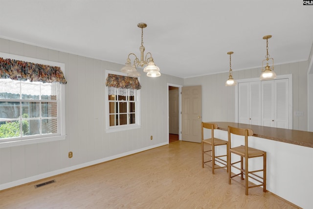 604 Shady Ln, Cayce, SC 29033 - kitchen featuring ornamental molding, light wood-style floors, a chandelier, hanging light fixtures, and a kitchen bar