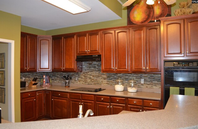 5102 Circle Dr, Columbia, SC 29206 - kitchen with black appliances, decorative backsplash, under cabinet range hood, light countertops, and reddish brown cabinets