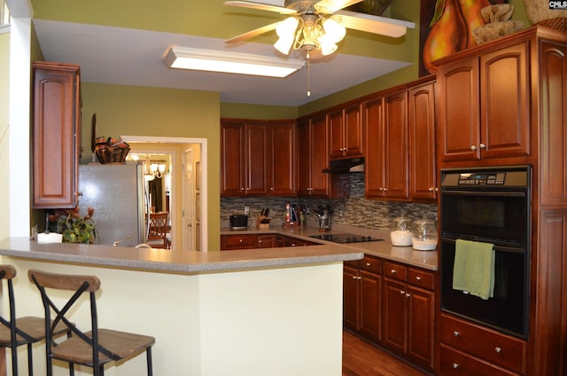 5102 Circle Dr, Columbia, SC 29206 - kitchen featuring black appliances, ceiling fan, a peninsula, backsplash, and a kitchen breakfast bar